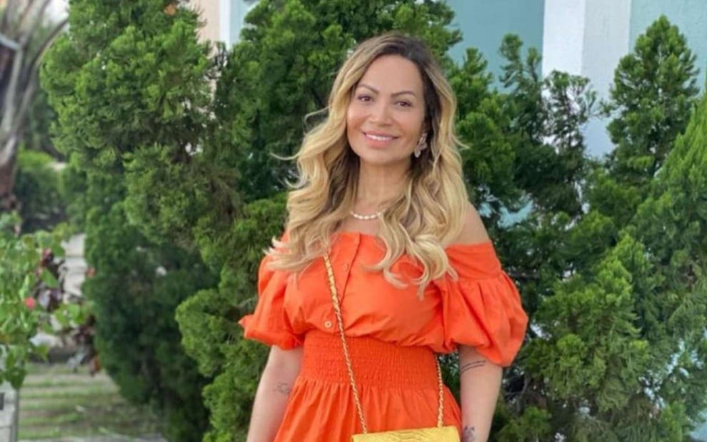 A cantora Solange Almeida, posando para foto com um vestido longo laranja