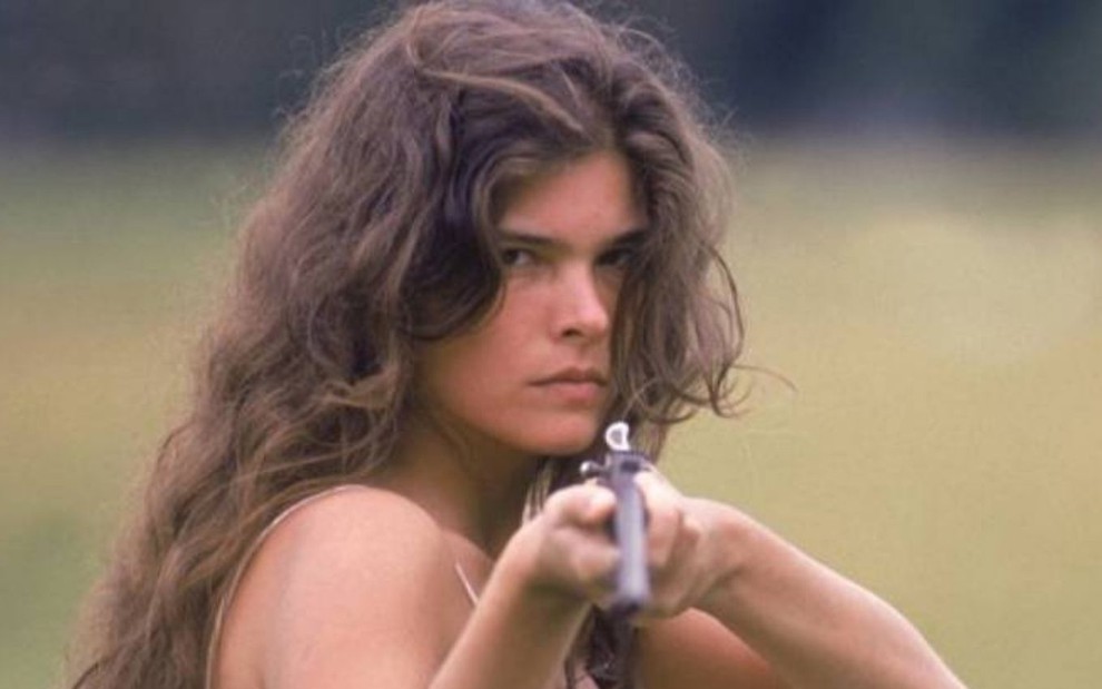 Caracterizada como Juma Marruá, Cristiana Oliveira segura arma em cena da novela Pantanal
