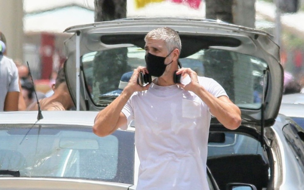 De máscara preta, camiseta branca e fones sobre os ombros, Reynaldo Gianecchini é flagrado grisalho