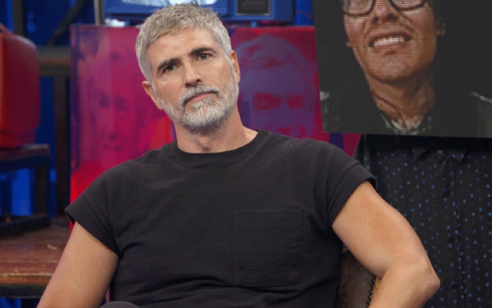 Reynaldo Gianecchini com uma blusa preta e olhar sério durante participação no Altas Horas, da Globo