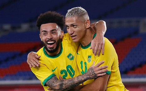 Claudinho e Richarlison usam a camisa amarela do Brasil, sorriem e se abraçaram durante os Jogos Olímpicos de Tóquio