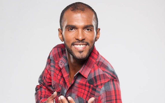 Richarlyson com uma camisa xadrez vermelha, sorrindo durante o programa Dancing Brasil, da Record