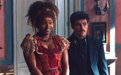 Lupita (Roberta Rodrigues) está em pé ao lado de Bernardinho (Gabriel Fuentes) em cena da novela Nos Tempos do Imperador