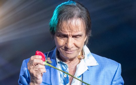 Roberto Carlos no momento de distribuição de rosas em show; ele usa um blazer azul