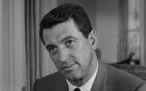 O ator Rock Hudson em cena do filme O Segundo Rosto, de 1966; ele usa terno e gravata e a imagem é em preto e branco