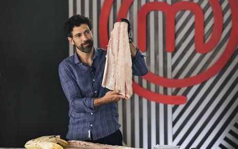Henrique Oliveira segurando uma carne nas mãos