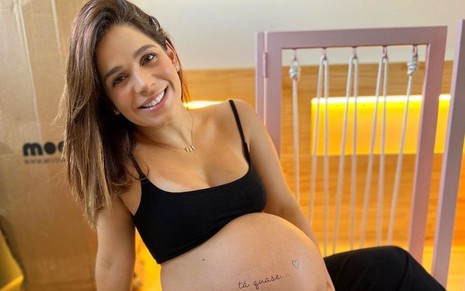 Sabrina Petraglia em foto publicada no Instagram; ela está sentada, veste um top preto e segura a barriga de nove meses de gravidez