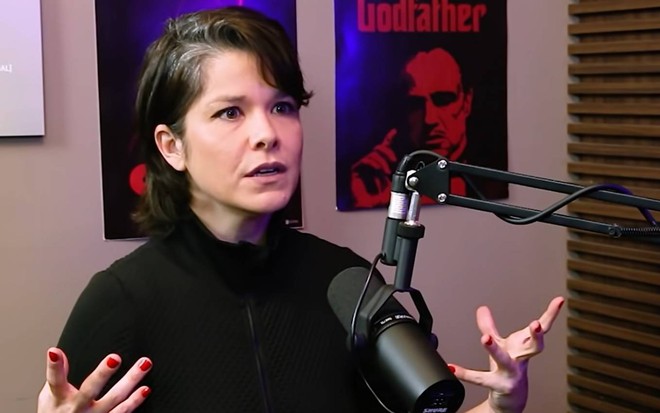 Atriz Samara Fellipe surge sentada, levanta os braços e olha para frente em entrevista ao humorista Rafinha Bastos