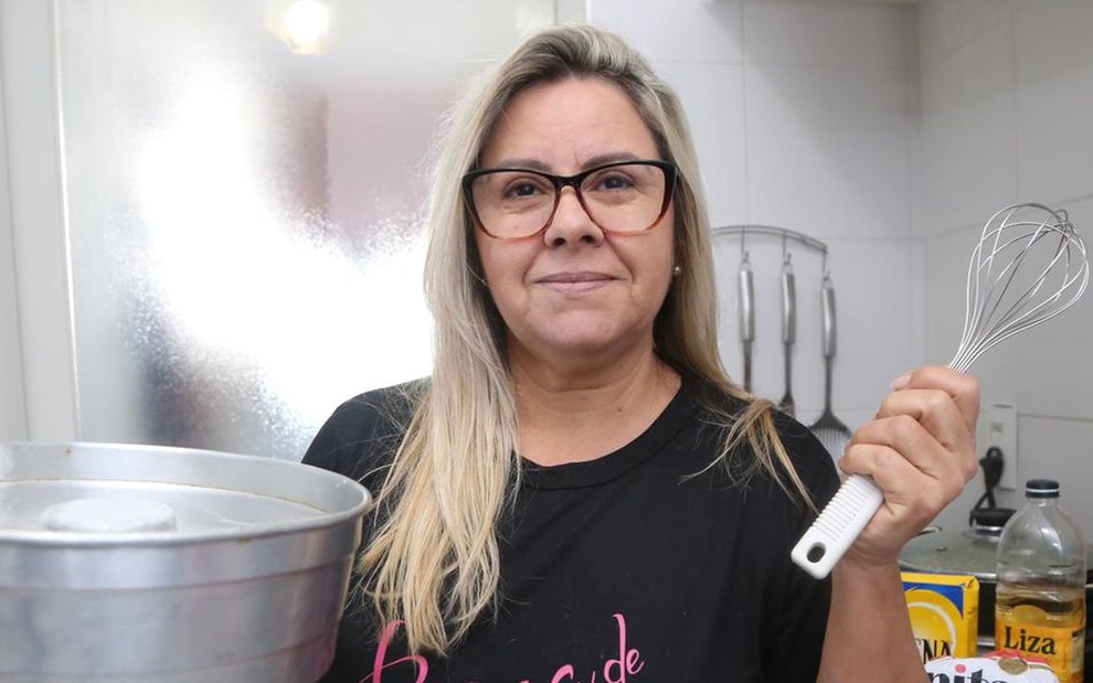 A cozinheira Sandra Rodrigues Campos está com uma forma de bolo e uma escumadeira