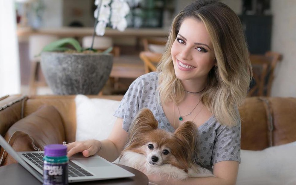 Cantora Sandy Leah segura a cachorra de estimação Zelda, sentada em frente ao computador