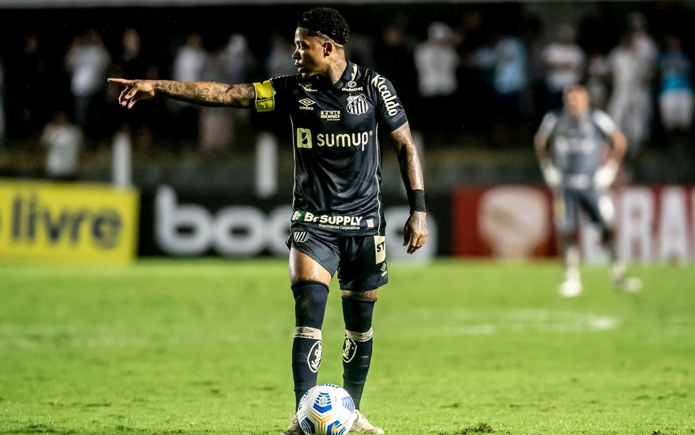 Jogador Marinho, do Santos, vestindo uniforme preto, com a bola aos pés durante partida da equipe
