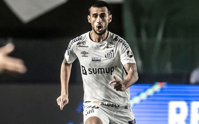 O jogador de futebol do Santos FC Camacho chuta uma bola em campo durante partida de futebol