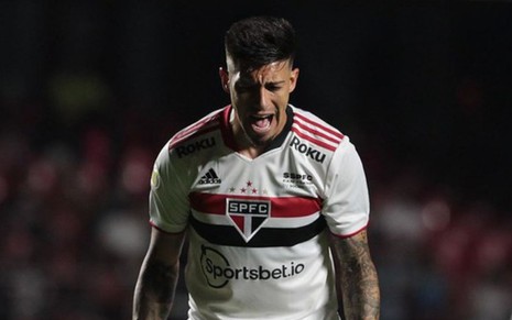 Jogador Rigoni, do São Paulo, vestindo uniforme branco com detalhes vermelho e preto; gritando durante jogo