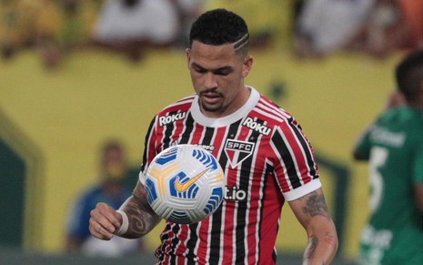 Luciano, jogador do São Paulo, vestindo uniforme vermelho e preto da equipe e dominando a bola durante partida