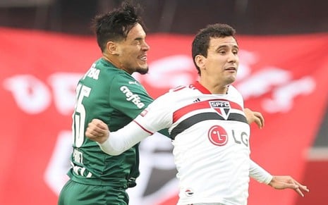 Gustavo Goméz usa a camisa verde do Palmeiras, enquanto Pablo usa a camisa branca com listras pretas e vermelhas do São Paulo. Eles brigam por uma bola em jogo no Morumbi.