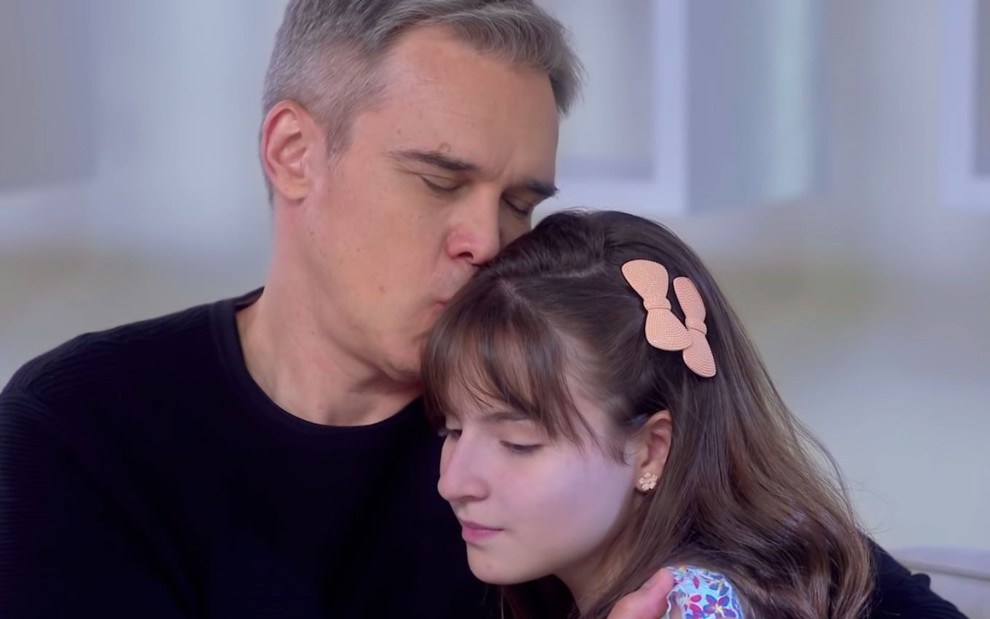 Os personagens Otto (Dalton Vigh) e Poliana (Sophia Valverde) se abraçam carinhosamente em cena da novela As Aventuras de Poliana