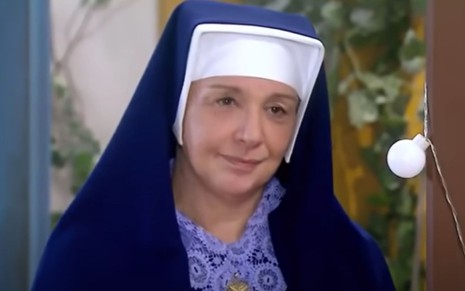 Eliana Guttman grava cena vestida de freira, com expressão tensa, como Madre Superiora em Carinha de Anjo, do SBT
