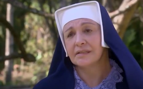 Eliana Guttman grava cena vestida de freira, com expressão emocionada, como Madre Superiora