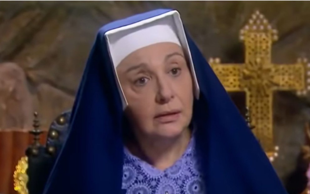 Eliana Guttman grava cena vestida de freira, com expressão espantada, como a madre superiora de Carinha de Anjo, do SBT