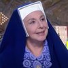Eliana Guttman grava cena vestida de freira, sorrindo, como Madre Superiora em Carinha de Anjo, do SBT