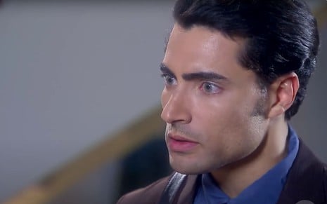 Carlo Porto em cena de de Carinha de Anjo: ator está em close, de terno e olha para alguém com feição de surpresa