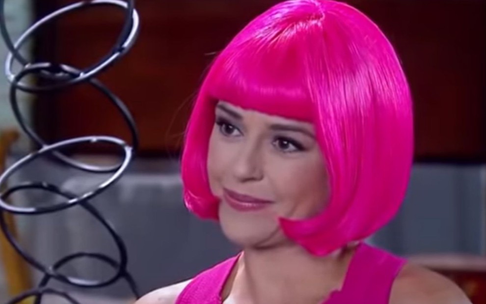 Priscila Sol grava cena com expressão séria, de peruca rosa, como Estefânia de Carinha de Anjo