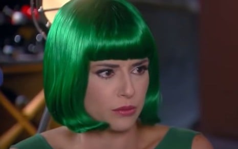 Priscila Sol grava cena com peruca verde, expressão séria, como Estefânia em Carinha de Anjo