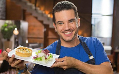 O ator Thiago Mendonça como o chef de cozinha Vitor, de Carinha de Anjo; ele segura bandeja com quitutes