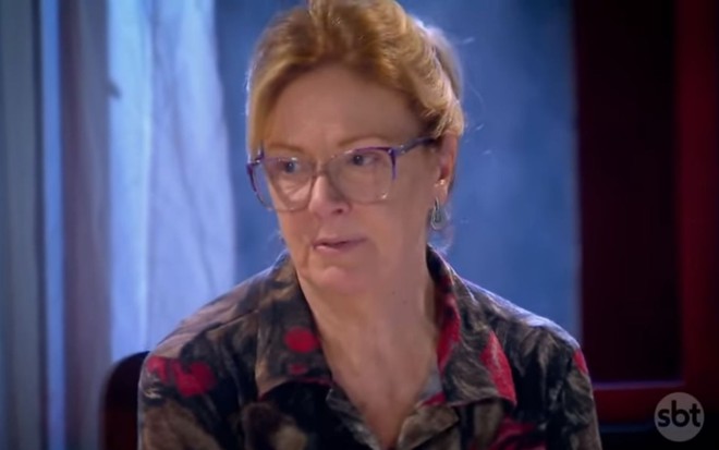 Elaine Cristina grava cena de óculos e cabelo preso, com expressão séria em Chiquititas, como Helena