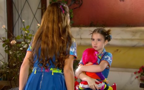 Sophia Valverde grava abraçada com boneca e olhando para Júlia Gomes, de costas na foto, como Maria e Marian de Chiquititas