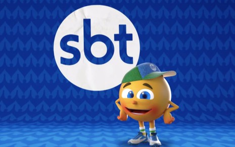 Mascote do SBT na Copa América 2021, Amarelinho posa com um logo da emissora ao fundo
