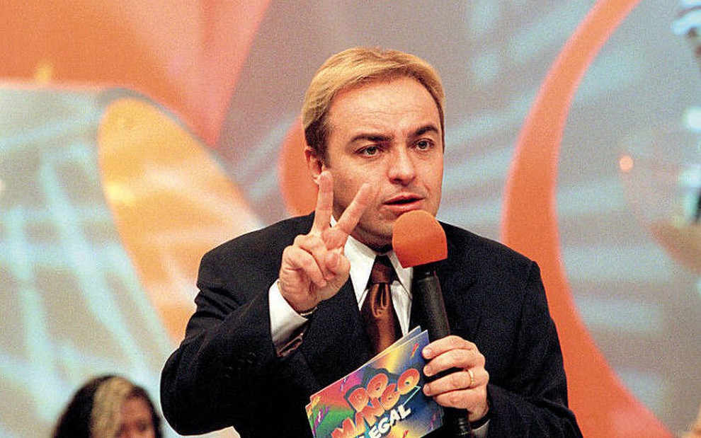 Gugu Liberato no cenário do Domingo Legal, nos anos 1990; ele ainda tinha cabelos loiros e usava terno e gravata na TV