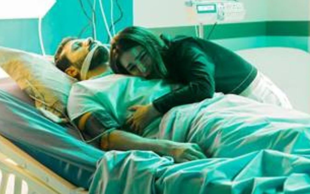 Murilo Cezar grava cena deitado em cama de hospital, como Thaís Melchior o abraçando, como Marcelo e Luísa