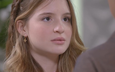 Sophia Valverde, caracterizada como Poliana, encara Igor Jansen, o João --fora do quadro-- com a expressão séria em Poliana Moça