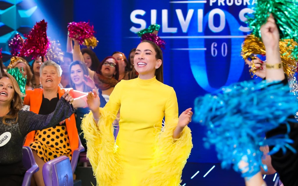 Patricia Abravanel usa um vestido amarelo e sorri para a câmera em gravações do programa especial de Silvio Santos