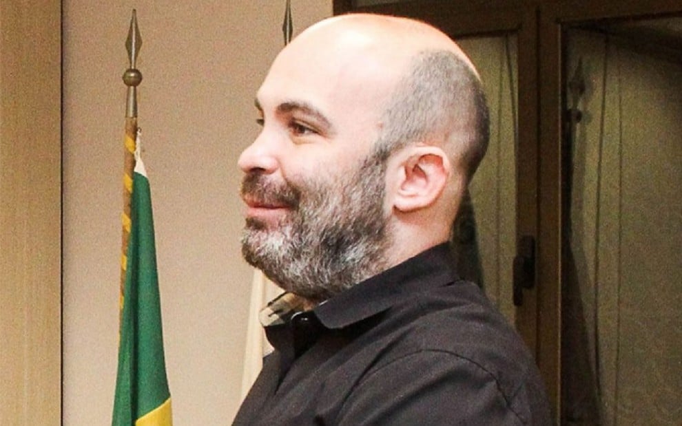 Gabriell Carvalho, ex-subsecretário de Saúde do Rio, com uma camisa preta e sorrindo para um correligionário