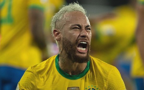 Neymar, veste uniforme amarelo com detalhes verdes e grita ao comemorar gol pela seleção brasileira