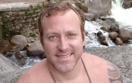 Imagem de Sérgio Hondjakoff, o Cabeção de Malhação, sem camisa em uma cachoeira