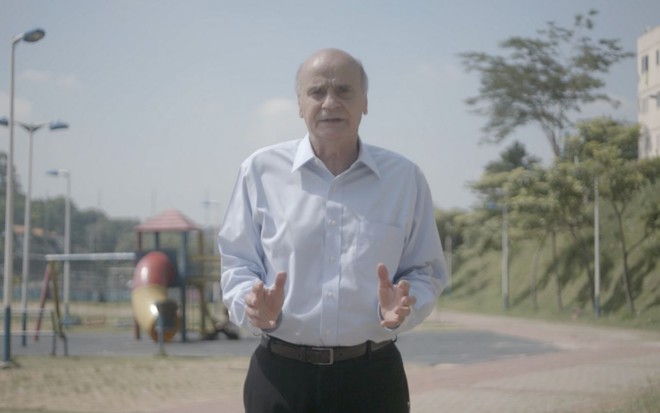 Em dia ensolarado, Drauzio Varella de roupa social em parque ao ar livre