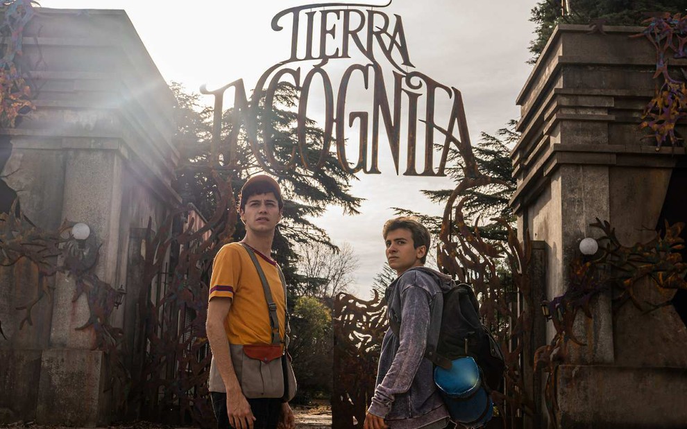 Eric (Pedro Maurizi) no lado esquerdo de camiseta amarela e boné e Axel (Tomás Kirzner) no lado esquerdo de blusa azul em frente à entrada de um parque de diversões abandonado na série Terra Incógnita