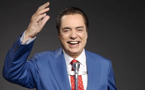 José Rubens Chachá vestido como Silvio Santos e com o microfone clássico do apresentador