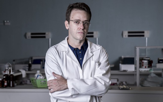 O ator Pablo Sanábio posa de jaleco de médico, com braços cruzados em cenário de hospital da série Sob Pressão, da Globo