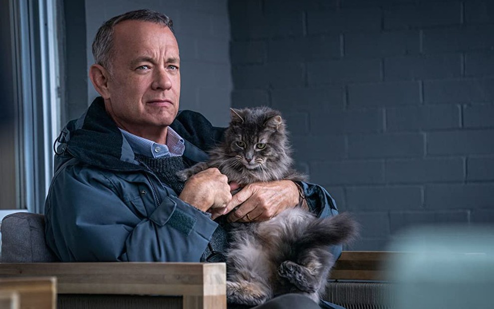 Tom Hanks segura um gato no colo e tem expressão séria em cena de O Pior Vizinho do Mundo