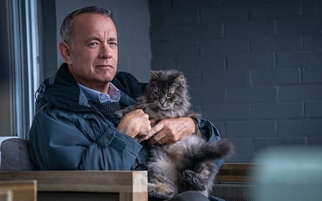Tom Hanks segura um gato no colo e tem expressão séria em cena de O Pior Vizinho do Mundo