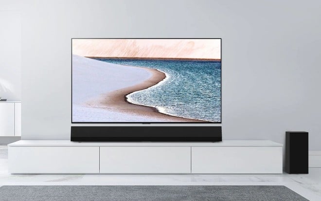 Caixa soundbar instalada abaixo da TV em uma sala com visual moderno