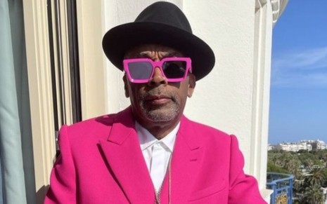 De chapéu preto, terno rosa e óculos escuros, Spike Lee posa para foto em Cannes