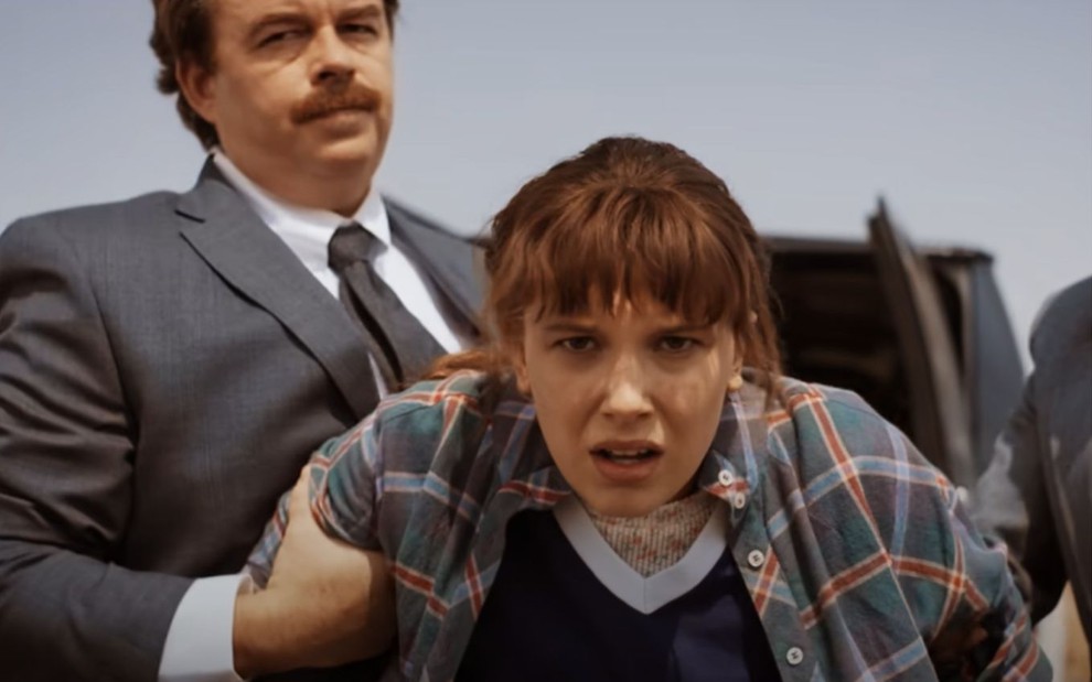Millie Bobby Brown é segurada pelo braço por um homem em cena da 4ª temporada de Stranger Things