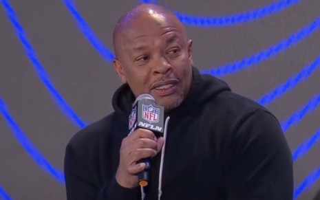 Dr. Dre segura microfone com logo da NFL enquanto fala em entrevista