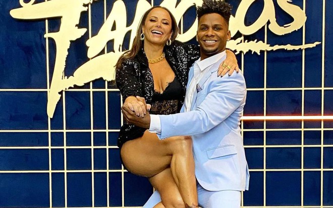 Viviane Araujo no colo de seu primeiro professor na Super Dança dos Famosos, Adeilton Ribeiro, numa reprodução de um passo de dança, ambos sorrindo