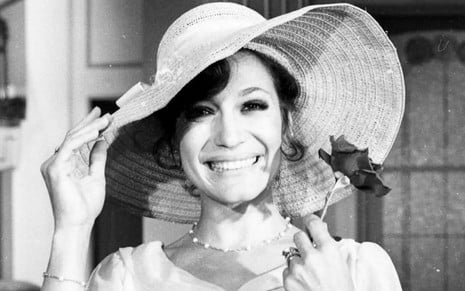 Susana Vieira em foto preto e branco, caracterizada como sua personagem na novela A Sucessora (1978). Ela usa um chapéu e sorri